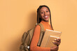 © Vergani Fotografia - portrait of black woman going to school and carrying books in beige studio background. learn, school, student life concept.