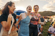 © Jacob Lund - Three female friends embrace, laugh, and celebrate the magic of the summer music festival