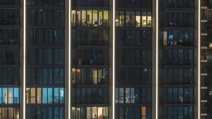 Wall Mural - Tall blocks of flats with glowing windows located in new residential district of city aerial timelapse. Evening light in rooms in towers and skyscrapers