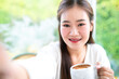 Portrait of beautiful happy Smiling asian woman Take a selfie with a smartphone relaxing sitting in cafe interior in coffee shop background,Business Lifestyle summer holiday concept
