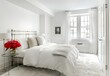bedroom with all white walls, the bed has a silver metal frame and has a long rectangular headboard