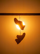 Pair of shoes hanging on power line wire high up in the sky against sunset sun.