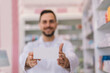 Male pharmacist holding up a box of medication in the pharmacy.