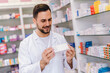 Young male pharmacist searching for medication in the pharmacy.