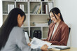 © Kritdanai - Two young Asian business woman talk, consult, discuss working with new startup project idea presentation analyze plan marketing and investment in the office.
