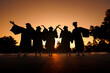 © nutt - silhouette cheerful graduates group in black gowns Graduation at sunset