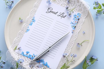 Plate with guest list, pen, lace and flowers on light blue background, flat lay. Space for text