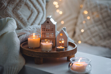 Wall Mural - Winter home aromatherapy, cozy atmosphere. Burning aroma candles on wooden tray, knitted blanket. Christmas scent, elegant interior design. Relaxation, detention, meditation, cosiness