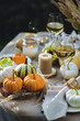 Cozy fall table decoration for Thanksgiving family dinner or romantic autumn wedding outdoors with small pumpkins, candles. White wine. Countryside style, cottage core, beautiful elegant setting