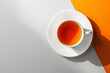 Cup of tea on a two-tone background with striking orange accent..