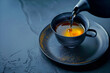 Pouring golden colored tea into a cup in dark blue tones with copy space