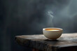 Steaming tea bowl on rustic wooden surface with a smoky background..