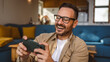 © Miljan Živković - Adult man with eyeglasses play video games on his phone at home