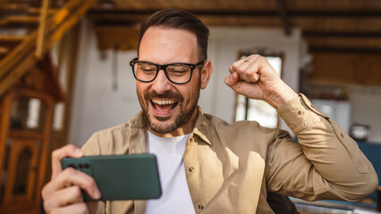 Wall Mural - Adult man with eyeglasses play video games on his phone at home