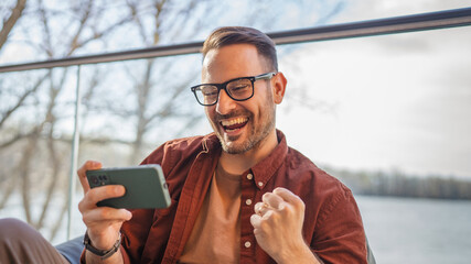 Wall Mural - Adult man with eyeglasses play video games on his phone at home