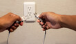 Hands insert a plug of the phone charger into socket.