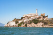 Alcatraz Island view from water in San Francisco Bay, California, USA. Rugged coastline, former prison, iconic lighthouse, clear sky, calm water, sparse vegetation, historical landmark.