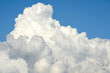 Large white clouds look soft against the background of a bright sky. The bottom of the clouds were gray like rain clouds before a storm.
