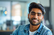 © Enigma - Portrait of a cheerful young man wearing a denim jacket, confidently smiling in a well-lit indoor space with a blurred background, depicting a casual, approachable, and modern lifestyle