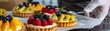 © kitidach - Artisan baker glazing a batch of fruit tarts, adding glossy finishes to the perfectly arranged fresh fruits on top