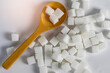 Sugar cubes with a wooden spoon circled on a white backdrop, representing sugar consumption