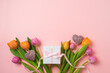 Happy Mother's day concept with tulip flowers, heart shape and gift box on pink background. Top view. Flat lay composition