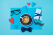 Happy Fathers day creative concept with coffee cup,  heart shape and gift box on blue background. Top view, flat lay