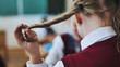 A girl touches a braid of her hair during class.