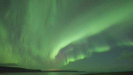 Wall Mural - The awe-inspiring display of vibrant colors and swirling patterns of Aurora Borealis above the sea.