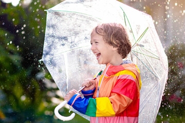 Wall Mural - Child playing in autumn rain. Kid with umbrella.