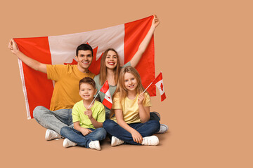 Wall Mural - Happy family with flags of Canada sitting on brown background