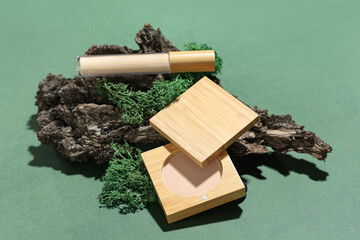 Wall Mural - Concealer with powder, tree bark and moss on green background. Eco style concept