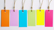Coloured pieces of note paper hanging on a line. close up. white background. colorfull lable. multi-colored tags. 