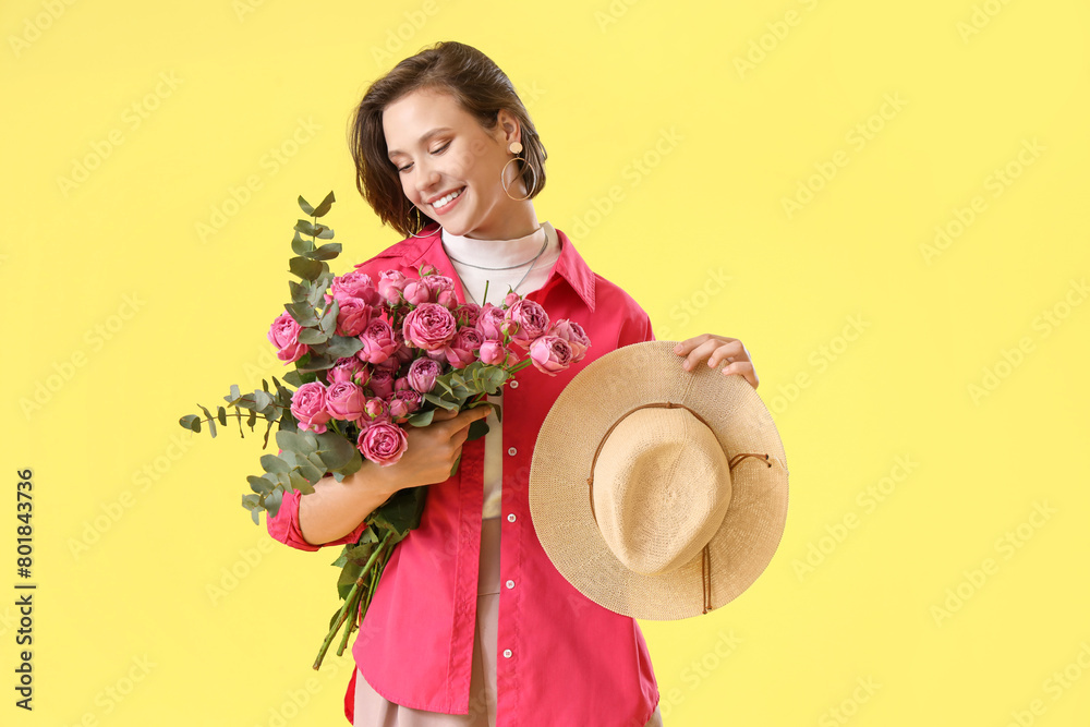 Young woman with pink roses on yellow background