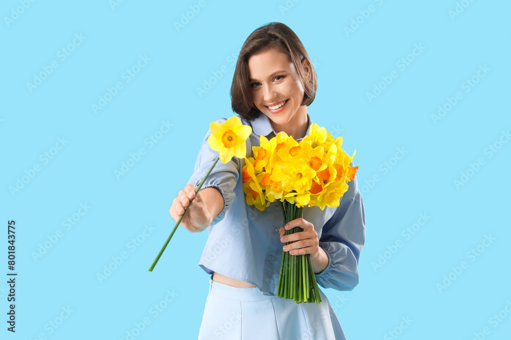 Young woman with daffodils on blue background