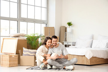 Wall Mural - Young couple using tablet computer in bedroom on moving day