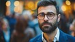 Blurred handsome young businessman with glasses and a beard standing in front of a crowd of business people. copy space for text.