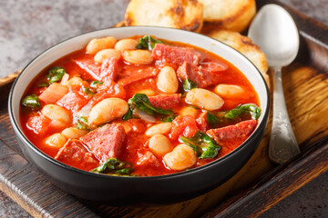 Wall Mural - Spanish stew of butter beans, chorizo and spinach in tomato sauce close-up in a bowl on the table. Horizontal