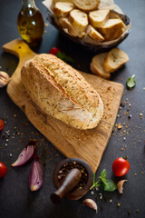 Canvas Print - freshly baked bread on wooden cutting board on dark table