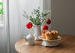 Tea time. A bouquet of flowers, brioche buns, a teapot on a round wooden table in the living room