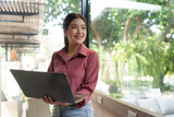 Fototapeta  - Happy Asian businesswoman on balcony using laptop to do morning work Business woman on holiday working outside that is natural Beautiful blogger woman thinking about content for work.