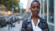 © Hryhor Denys - A black woman with short hair wearing a leather jacket, holding a cell phone