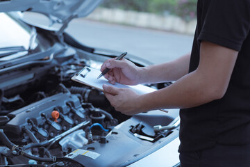 Automobile repairman writing job checklist on clipboard