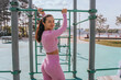 Woman using outdoor gym equipment, exercising with focus and determination under sunny skies