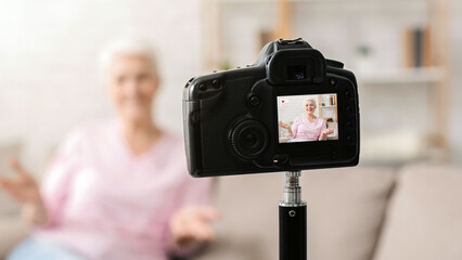 Poster - senior woman is seated on a couch, facing a camera directly in front of her. she appears to be posin