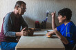 Photo of a grandfather sharing coffee and breakfast with his grandson at a plastic table with a coffee cup