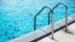 Chrome handrails of the swimming pool. Hotel spa and resort accommodation. Ladder on the poolside. Relaxation in the summertime.