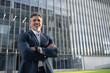 © Stock 4 You - Proud portrait of older senior businessman professional ceo, manager, leader looking camera near city office. Smiling confident 40s latin hispanic mature business man standing crossed arms, copy space