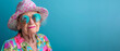 © Nataliia_Trushchenko - A woman in a pink hat and a colorful shirt. She is wearing sunglasses and has a big smile on her face. Concept of fun and lightheartedness. Old lady wearing colorful clothes in a studio environment