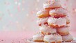 A stack of pink frosted donuts with sprinkles on top